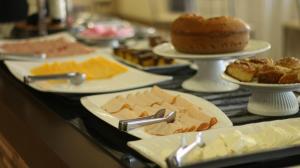 a table topped with plates of cheese and other desserts at Bekassin Botucatu Hotéis Ltda in Botucatu +22 photos