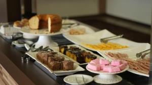 um buffet com diferentes tipos de produtos de pastelaria e outros alimentos em Bekassin Botucatu Hotéis Ltda em Botucatu