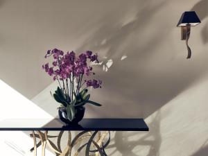 a vase of purple flowers on a table next to a lamp at Samaria Hotel in Chania