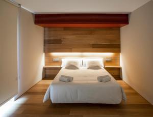 Schlafzimmer mit einem großen weißen Bett und Holzwänden in der Unterkunft Hotel Estació in Olot