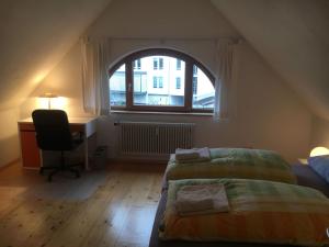 1 dormitorio con 2 camas, escritorio y ventana en Haus Schönwald, en Freiburg im Breisgau