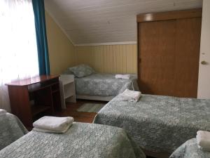 a room with three beds and a desk at Casa Florecer in Contulmo