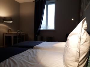 a bedroom with a white bed with a window at Villa Marguerite in Saint-Omer