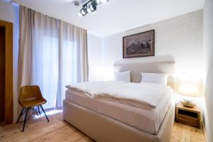 a bedroom with a white bed and a chair at Hotel Rote19 in Regensburg