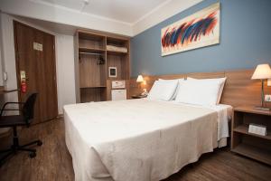 una camera d'albergo con un grande letto bianco e una sedia di Summit Hotel Monaco a Guarulhos