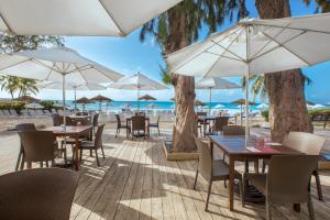 a restaurant with tables and umbrellas on the beach at Bougainvillea Barbados in Christ Church