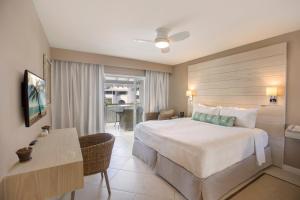 a hotel room with a large bed and a desk at Bougainvillea Barbados in Christ Church