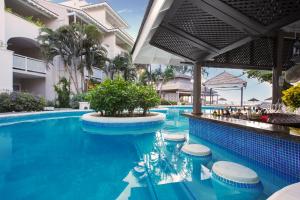 a pool at a resort with blue water and stools at Bougainvillea Barbados in Christ Church