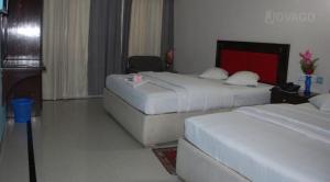 une chambre d'hôtel avec deux lits et une chaise dans l'établissement Hotel Auster echo, à Cox's Bazar