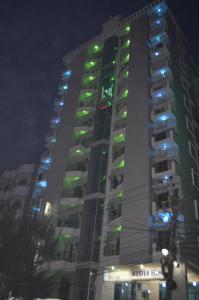 een hoog gebouw met groene en blauwe lichten erop bij Hotel Auster echo in Cox's Bazar