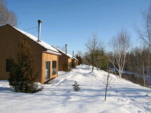 una carretera cubierta de nieve junto a un edificio en Le Genevrier, en Baie-Saint-Paul