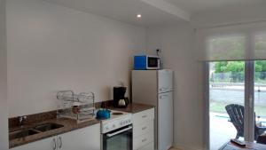 a kitchen with a refrigerator and a microwave at Condominio del Faro - Quequen in Necochea +12 photos