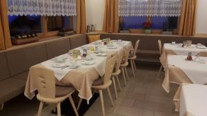 a row of tables in a restaurant with white table cloth at Garni Margherita in Corvara in Badia