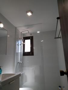 a white bathroom with a shower and a sink at Acogedor apartamento en el casco histórico in Toledo