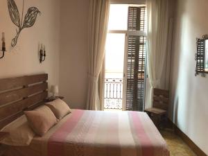 1 dormitorio con cama y ventana grande en Hostal Parellades, en Sitges