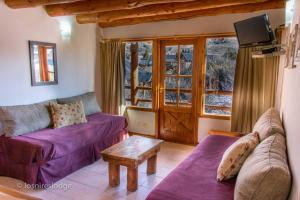 uma sala de estar com sofás roxos e uma televisão em Los Nires Lodge Cerro Catedral em San Carlos de Bariloche