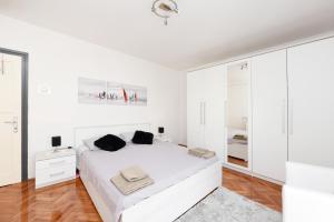 um quarto branco com uma cama branca e armários brancos em Apartment Katia em Zadar