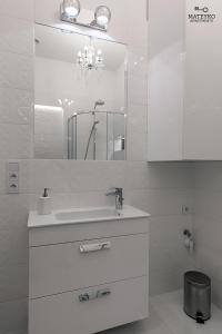 Baño blanco con lavabo y espejo en Mateyko Apartment en Cracovia
