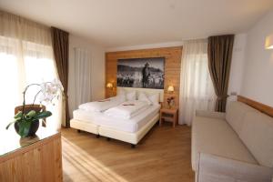 a bedroom with a white bed and a couch at Active Hotel Pineta in Baselga di Pinè