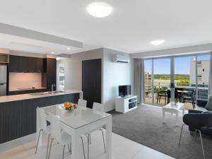 a kitchen and living room with a white table and chairs at Oaks Mackay Rivermarque Hotel in Mackay