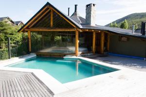 an outdoor swimming pool with a pavilion and a house at Los Nires Lodge Cerro Catedral in San Carlos de Bariloche