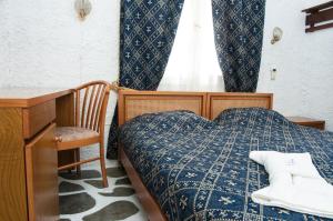 Schlafzimmer mit einem Bett, einem Schreibtisch und einem Fenster in der Unterkunft Manousos' Rooms in Galissas