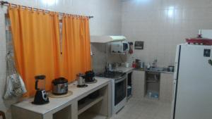 a kitchen with an orange curtain and a refrigerator at Nossa Casa in Cunha