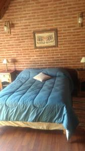 un letto blu in una camera da letto con muro di mattoni di Chalet Bosque Peralta Ramos a Mar del Plata