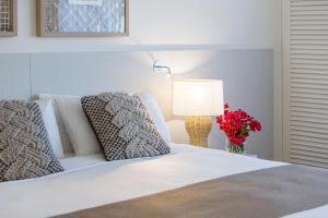 a white bed with a lamp and a vase of flowers at Oaks Sunshine Coast Oasis Resort in Caloundra