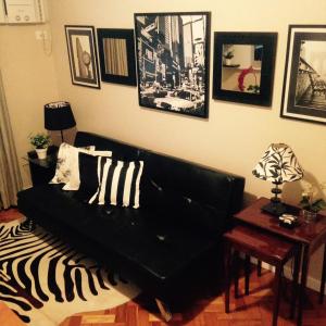 sala de estar con sofá negro y cuadros en la pared en COPANEMA - Próximo Ipanema Arpoador, en Río de Janeiro