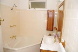 a white bathroom with a tub and a sink at Berry, 16 East Street in Crescent Head