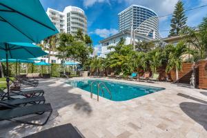 a swimming pool with chairs and trees and buildings at Nobleton Hotel in Fort Lauderdale