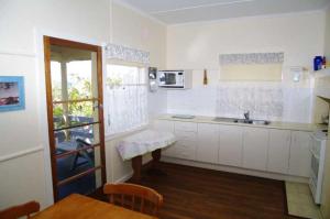 a kitchen with white cabinets and a table and a window at Lorikeet Retreat, 11 Hodgson Street in Crescent Head
