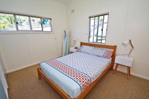 a bedroom with a bed and a lamp and two windows at Bella Vista, 9 East Street in Crescent Head