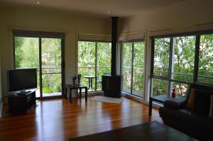 a living room with a couch and a tv and windows at The Track - beautiful townhouse in Bright in Bright