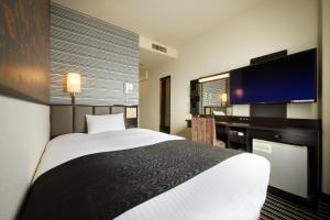a hotel room with a bed and a flat screen tv at APA Hotel Isesaki-Eki Minami in Isesaki