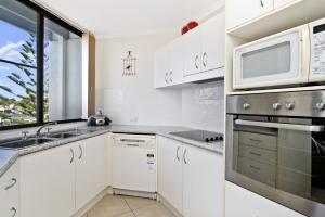 a white kitchen with a microwave and a sink at Sundial 503 8-10 Hollingworth Street in Port Macquarie