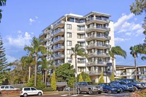 a tall white building with cars parked in a parking lot at Sundial 503 8-10 Hollingworth Street in Port Macquarie