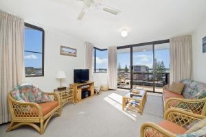 uma sala de estar com cadeiras e uma televisão e janelas em Sundial 602 8-10 Hollingworth Street em Port Macquarie