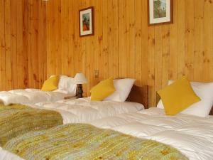 três camas num quarto com paredes com painéis de madeira em Hotel del Paine em Torres del Paine