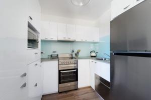 een keuken met witte kasten en een roestvrijstalen oven bij Flynns Beach Apartments 4 41 Pacific Drive in Port Macquarie