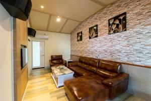 a living room with leather furniture and a brick wall at Melinda Resort in Hengchun