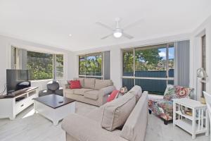 a living room with a couch and a tv at Aqualuna At Lighthouse Beach 8 Capalla Court in Port Macquarie