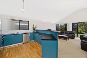 an open kitchen and living room with blue cabinets at Amara 6 Wesley Avenue in Port Macquarie