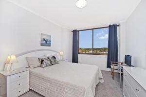 a white bedroom with a bed and a window at Akuna 18 6 Joffre Street in Port Macquarie