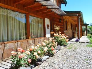 una casa de madera con flores delante en Las Vertientes Lodge en San Martín de los Andes