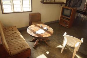 a living room with a table and a couch and a tv at Masaka Backpackers, Tourists Cottage & Campsite in Masaka