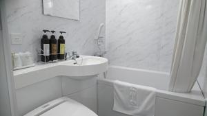 a white bathroom with a toilet and a sink at Terminal Hotel Matsuyama in Matsuyama