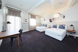 sala de estar con 2 sofás blancos y escritorio en Bridgeview Hotel Willoughby, en Sídney