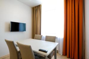 a white table with chairs and a television on a wall at Apart Petrovskie 1 on Sovetskaya 90 in Tomsk